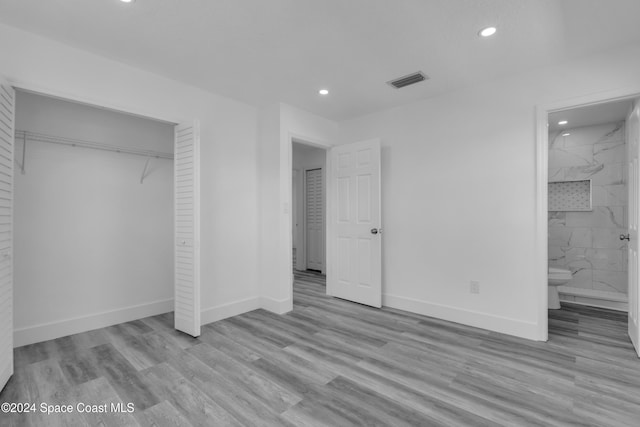 unfurnished bedroom featuring connected bathroom, a closet, and light hardwood / wood-style flooring