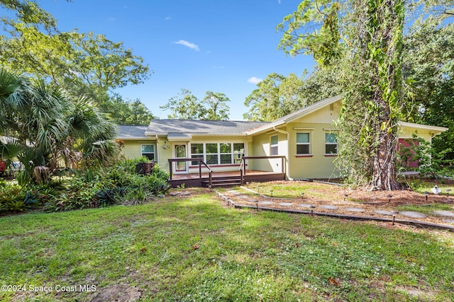 rear view of property featuring a yard and a deck