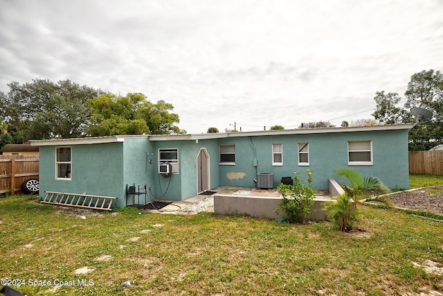 back of house with cooling unit, a lawn, and central AC