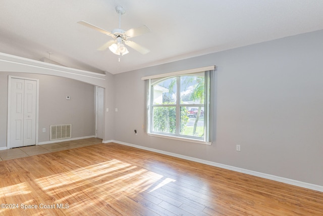 empty room with ceiling fan, lofted ceiling, and light hardwood / wood-style flooring