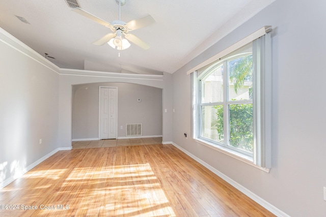 empty room featuring lofted ceiling, light wood-type flooring, and ceiling fan