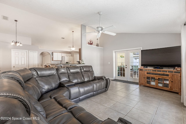 tiled living room with french doors, high vaulted ceiling, and ceiling fan with notable chandelier