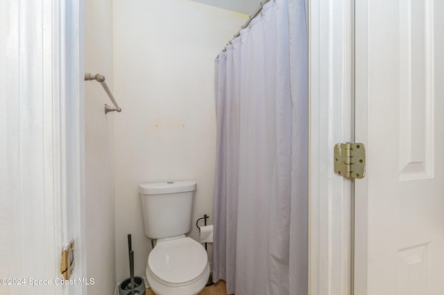 bathroom with toilet and a shower with shower curtain