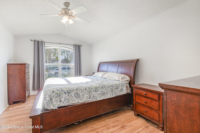 bedroom with light hardwood / wood-style floors, a textured ceiling, lofted ceiling, and ceiling fan