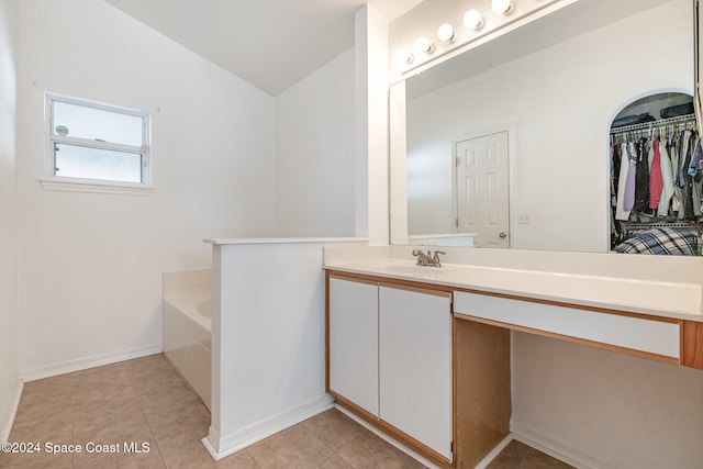 bathroom featuring vanity, a relaxing tiled tub, and tile patterned flooring