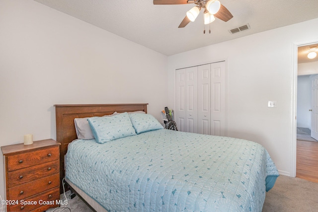 bedroom with light hardwood / wood-style flooring, a textured ceiling, a closet, and ceiling fan