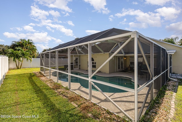 view of swimming pool featuring a yard, a patio area, and glass enclosure