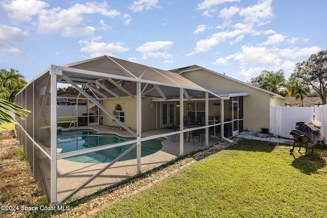 back of house featuring a fenced in pool, a yard, a patio, and glass enclosure