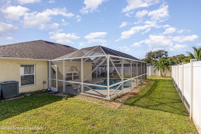 rear view of property with a yard, a lanai, a fenced in pool, and central AC unit