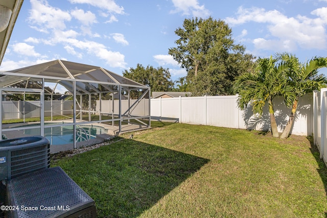 view of yard featuring a patio area, a lanai, a fenced in pool, and central AC unit