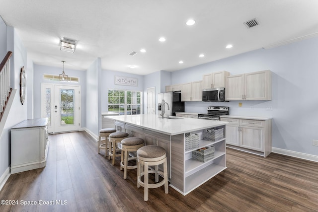 kitchen with a center island with sink, dark hardwood / wood-style flooring, appliances with stainless steel finishes, a kitchen breakfast bar, and sink