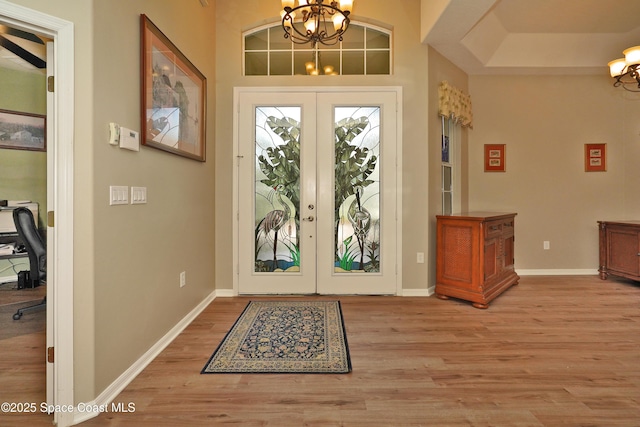 foyer with hardwood / wood-style flooring, french doors, and an inviting chandelier