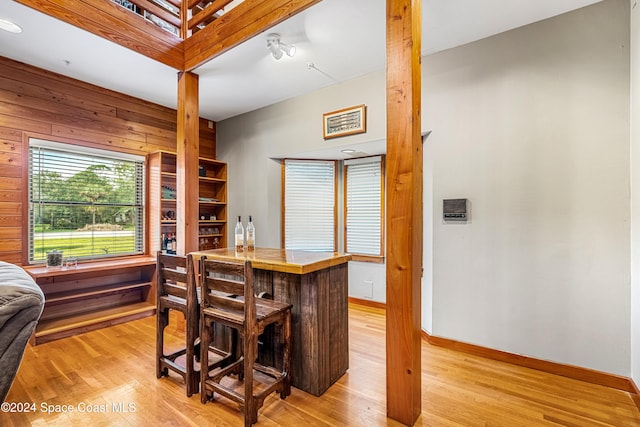 interior space featuring wood walls, light wood-type flooring, and bar area