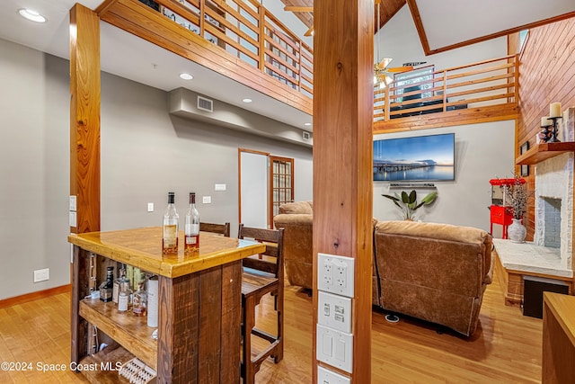 dining room with a towering ceiling, indoor bar, and light wood-type flooring