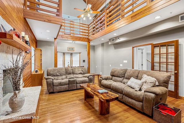 living room featuring light hardwood / wood-style flooring, a high ceiling, and ceiling fan