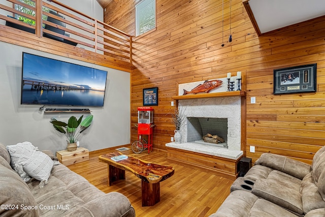 living room with a towering ceiling, wood walls, and hardwood / wood-style floors