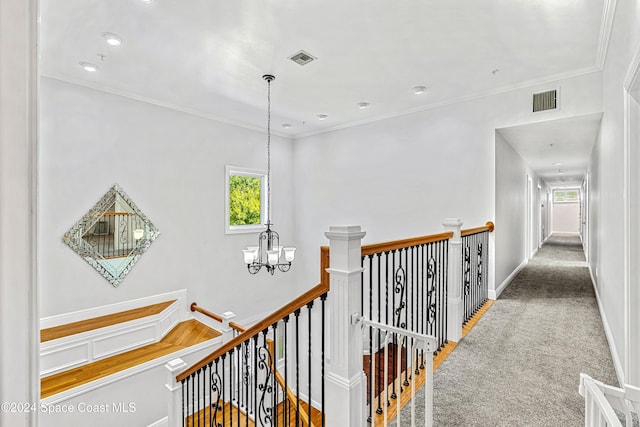 corridor with crown molding, carpet flooring, and a chandelier