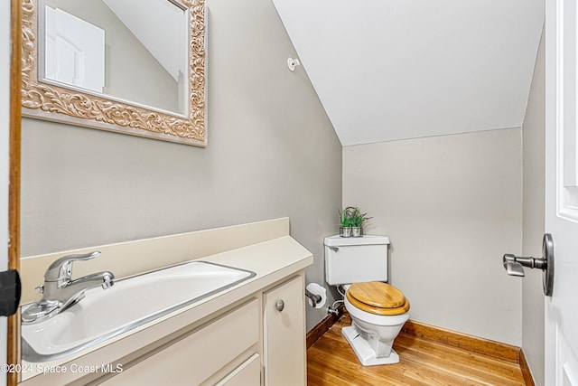 bathroom with toilet, hardwood / wood-style flooring, vanity, and vaulted ceiling