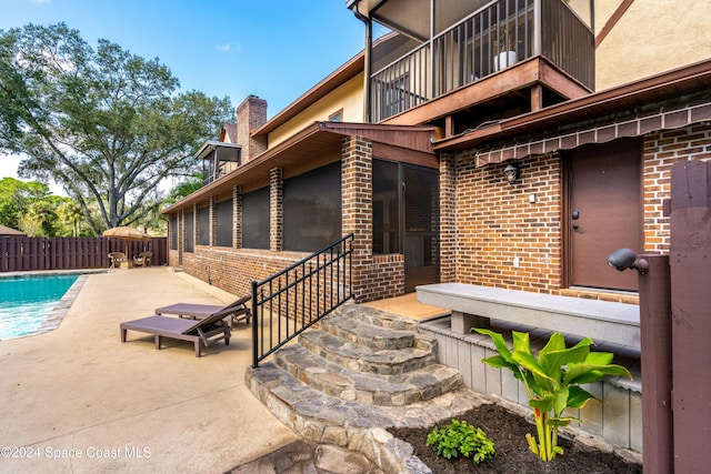 property entrance featuring a balcony, a patio, and a fenced in pool