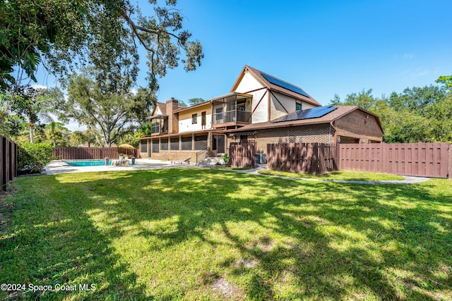 rear view of house with a patio area, a lawn, and a fenced in pool