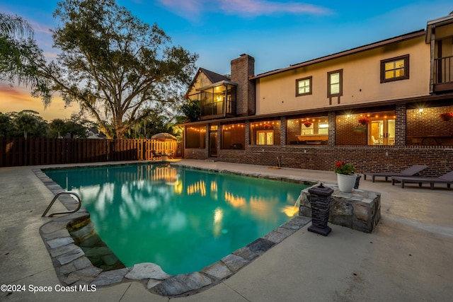 pool at dusk featuring a patio