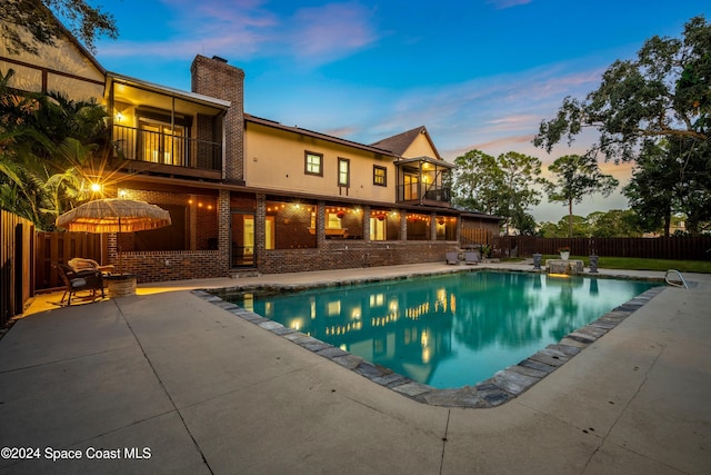 pool at dusk featuring a patio