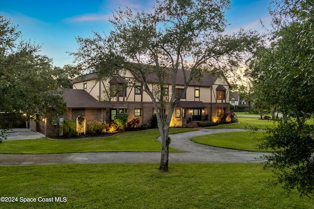 tudor home with a garage and a lawn