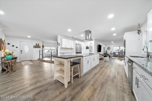 kitchen with a center island, sink, hardwood / wood-style flooring, appliances with stainless steel finishes, and white cabinetry