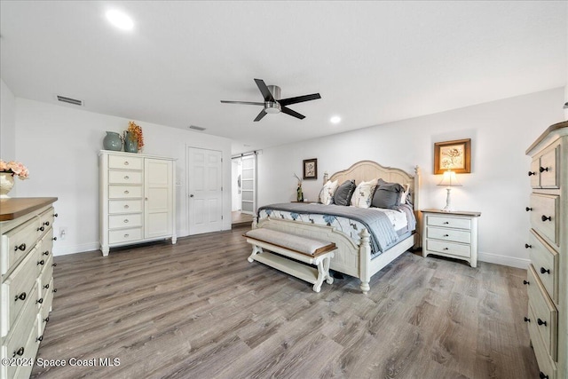 bedroom featuring a barn door, hardwood / wood-style flooring, and ceiling fan