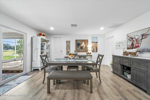 dining room featuring a textured ceiling and light wood-type flooring