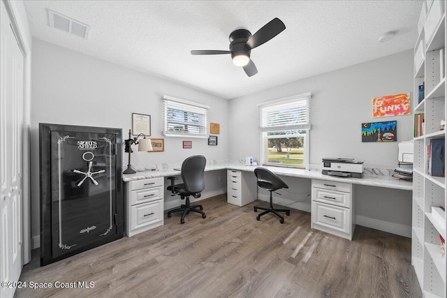 office with a textured ceiling, built in desk, dark hardwood / wood-style floors, and ceiling fan