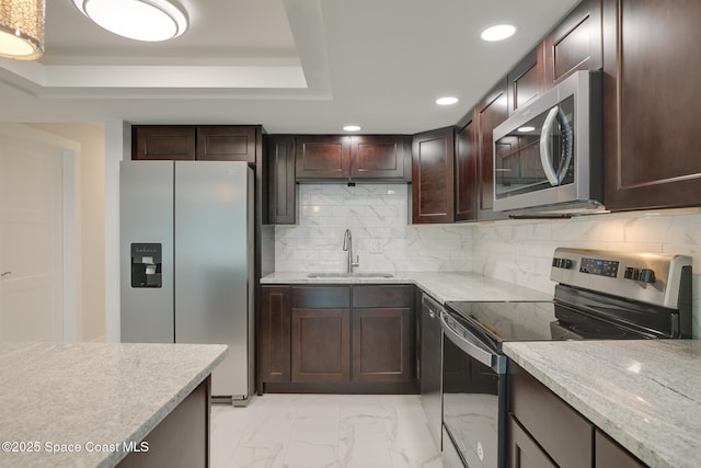 kitchen featuring light stone countertops, stainless steel appliances, sink, a tray ceiling, and dark brown cabinets