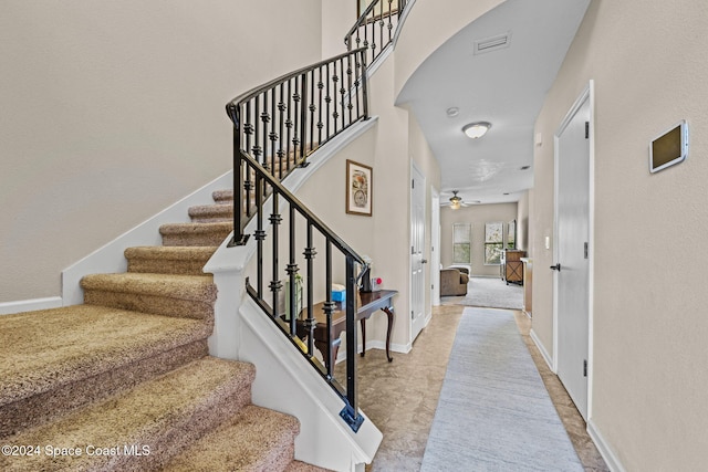 stairs featuring ceiling fan