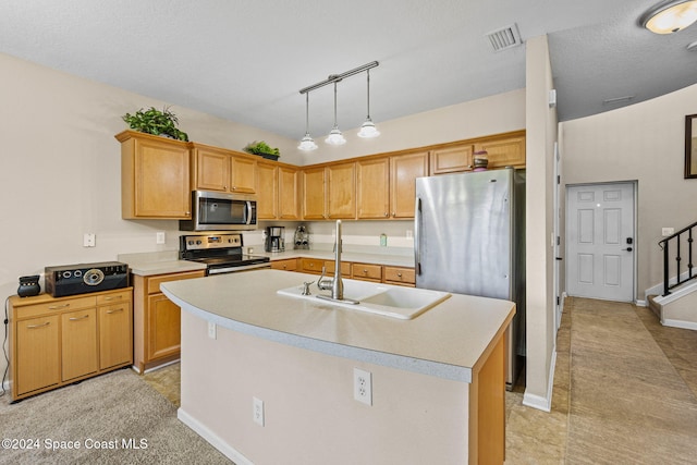 kitchen with sink, a textured ceiling, stainless steel appliances, decorative light fixtures, and a kitchen island with sink