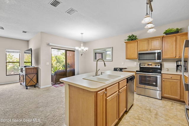 kitchen with appliances with stainless steel finishes, sink, decorative light fixtures, an inviting chandelier, and a kitchen island with sink