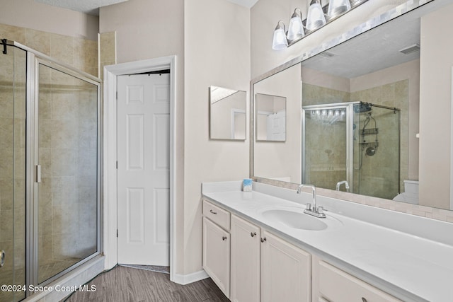 bathroom with a shower with door, wood-type flooring, a textured ceiling, and vanity