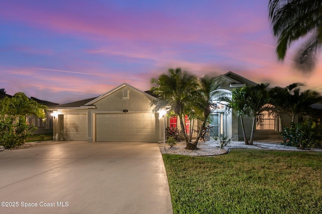 ranch-style house featuring a yard, an attached garage, driveway, and stucco siding
