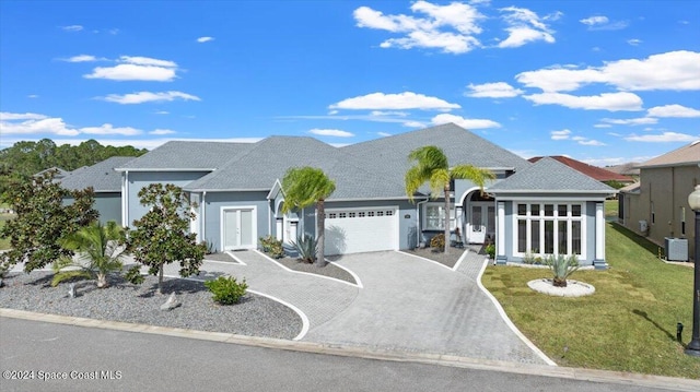 view of front of house featuring a front lawn, a garage, and central AC unit