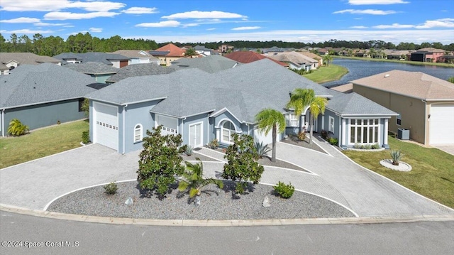 view of front of home with a front lawn, central AC unit, a water view, and a garage