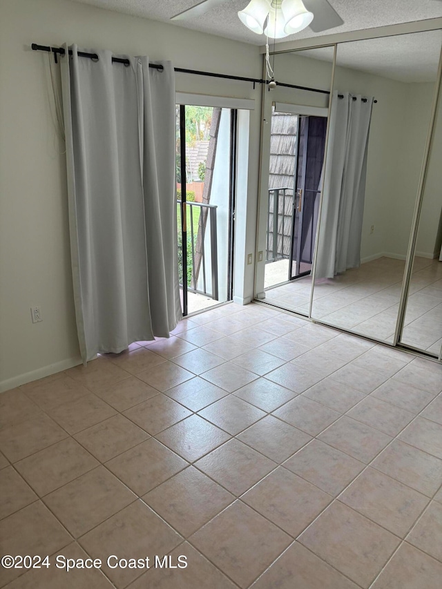 tiled empty room with a textured ceiling and ceiling fan