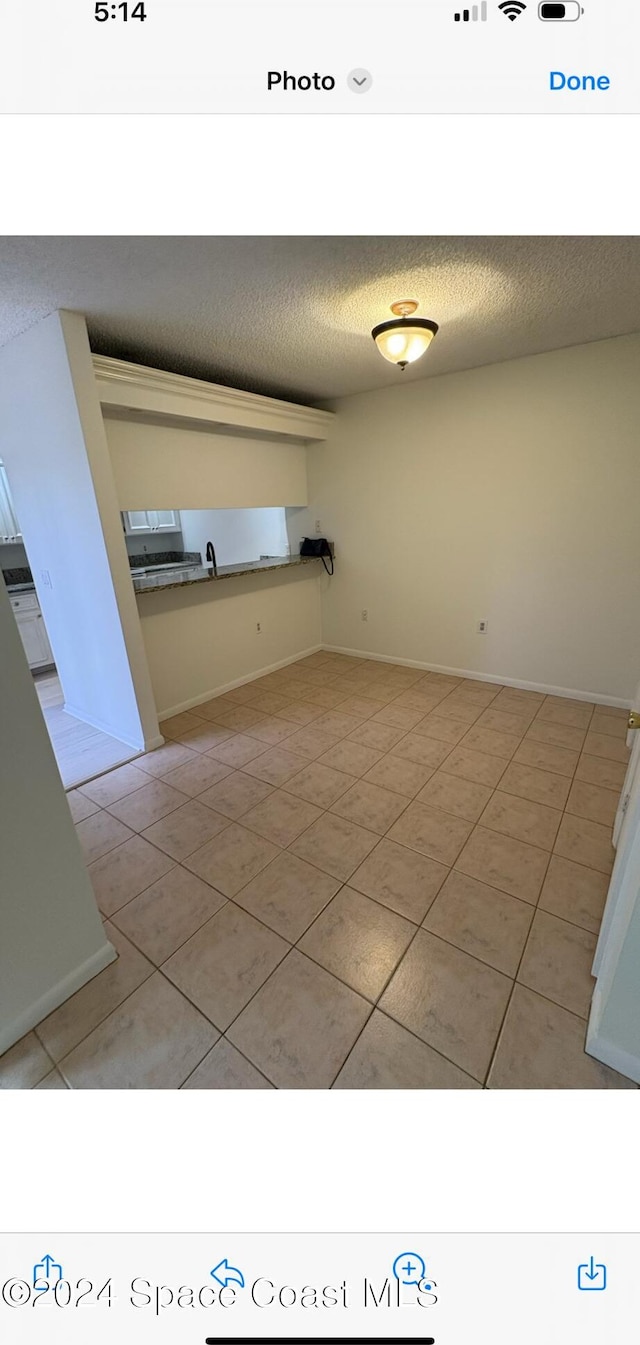 empty room with light tile patterned flooring and a textured ceiling