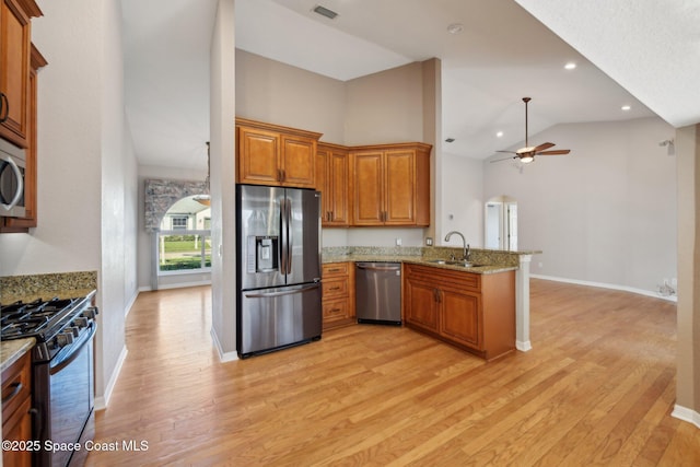 kitchen featuring ceiling fan, sink, light stone counters, kitchen peninsula, and appliances with stainless steel finishes