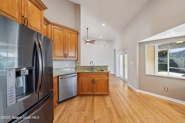 kitchen with ceiling fan, sink, stainless steel appliances, light stone counters, and kitchen peninsula