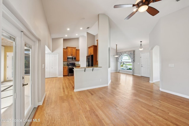 unfurnished living room with light hardwood / wood-style floors, high vaulted ceiling, and ceiling fan