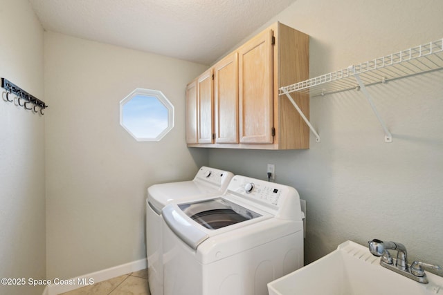 clothes washing area with sink, cabinets, a textured ceiling, washer and clothes dryer, and light tile patterned floors