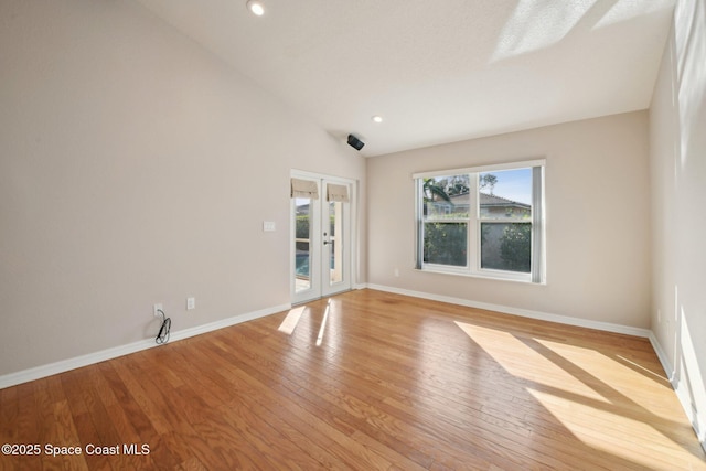 spare room with light wood-type flooring and vaulted ceiling