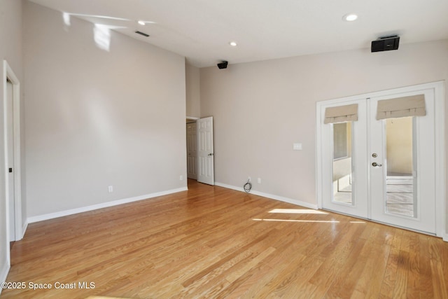 unfurnished room with vaulted ceiling, light hardwood / wood-style flooring, and french doors