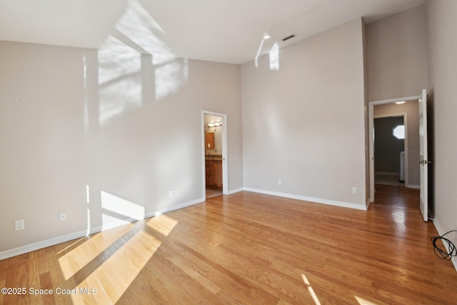 spare room featuring a towering ceiling and wood-type flooring