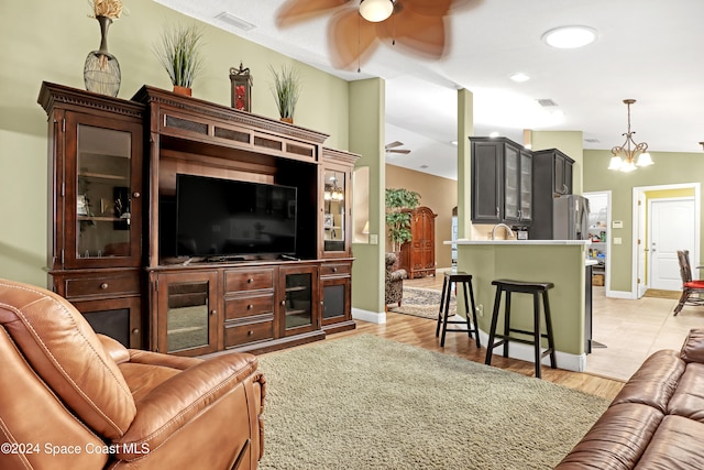 living room featuring ceiling fan with notable chandelier, light hardwood / wood-style flooring, and vaulted ceiling