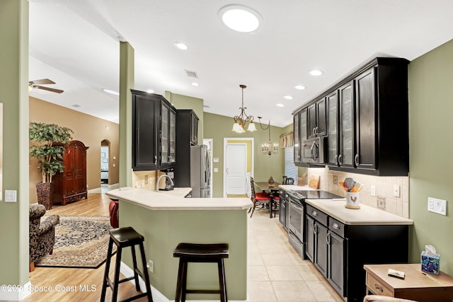 kitchen with lofted ceiling, light hardwood / wood-style flooring, a kitchen breakfast bar, backsplash, and appliances with stainless steel finishes